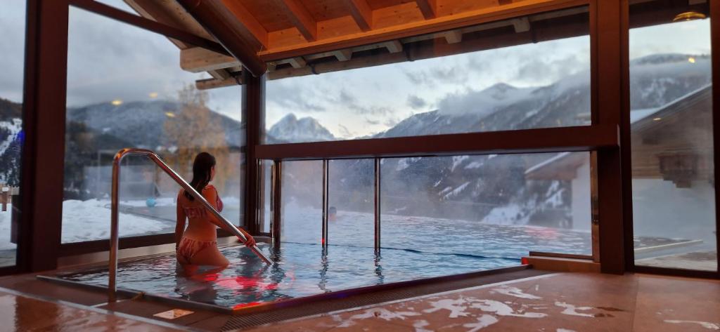 una mujer en una bañera de hidromasaje con vistas a la montaña en Hotel Kompatscherhof, en Luson