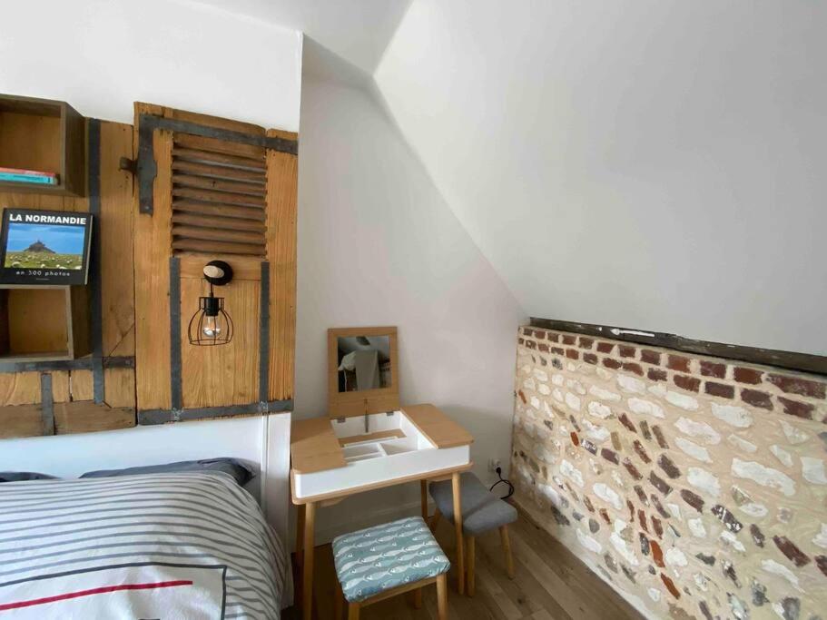 a bedroom with a bed and a desk with a sink at Yport, maison de pêcheur avec jolie terrasse. in Yport