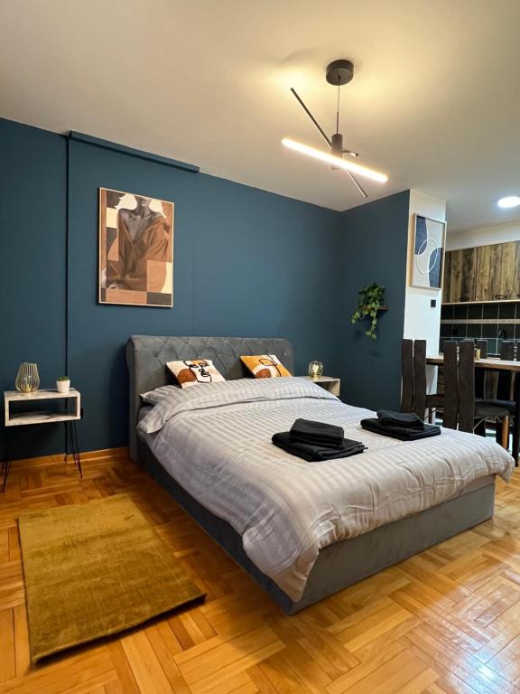a bedroom with a large bed with a blue wall at LP Premium Studio in Niš
