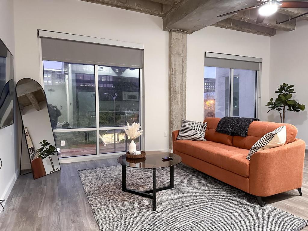 a living room with an orange couch and a table at The Best of Downtown Living in Baton Rouge