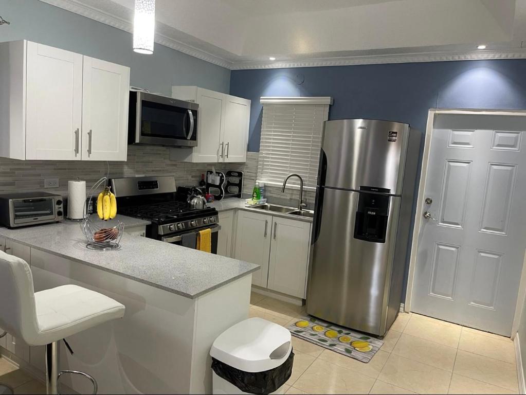 a kitchen with a stainless steel refrigerator and white cabinets at The Cameron @ Phoenix Park in Portmore