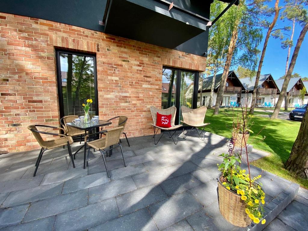 a patio with a table and chairs and a brick wall at Domki Poezja Ciszy in Dębki