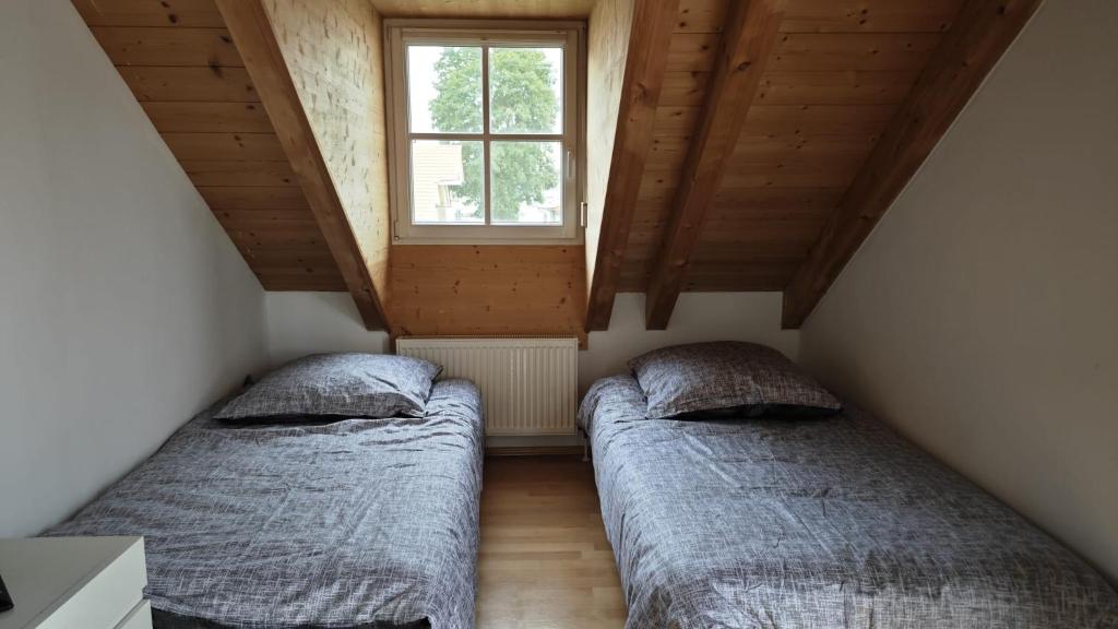 Duas camas num pequeno quarto com uma janela em Ferienhaus Weilheim mit Garten Spiel und Spass em Weilheim in Oberbayern