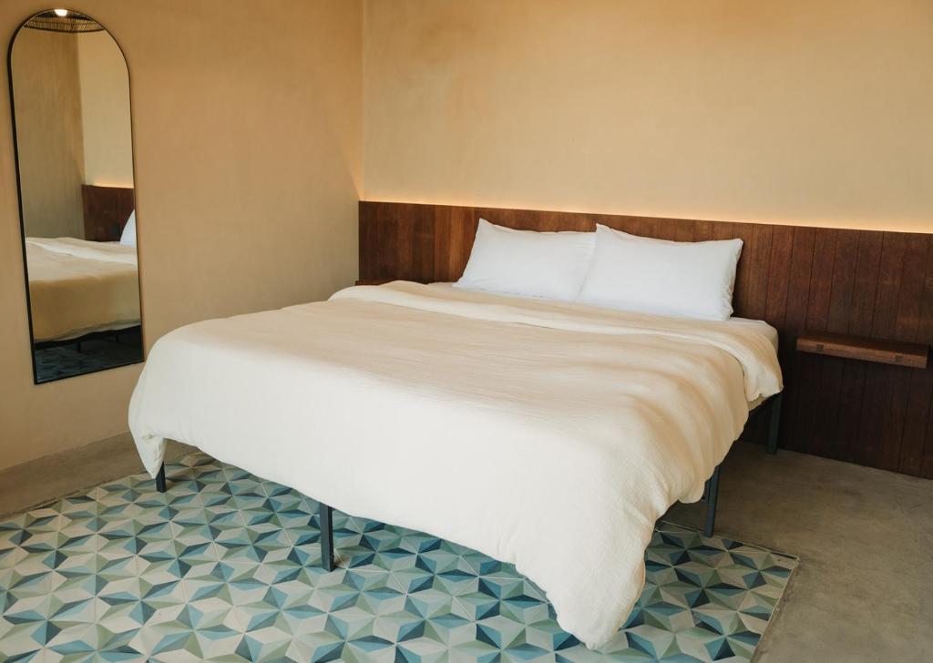Schlafzimmer mit einem großen weißen Bett und einem Spiegel in der Unterkunft Equ Hotel de Tierra in El Porvenir