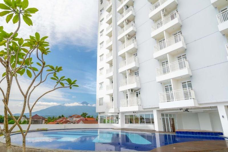 un hotel con piscina di fronte a un edificio di Jasmin Park Apartemen By Fix's Room a Kedungbadak