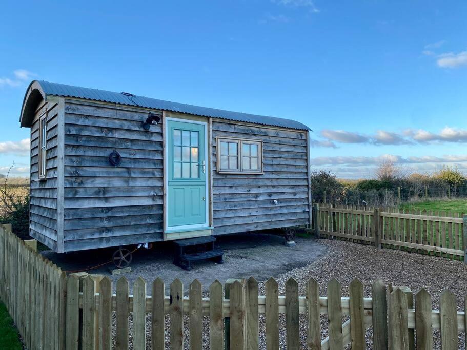 a tiny house sitting next to a wooden fence at Luxury Shepherd Hut in Kelham