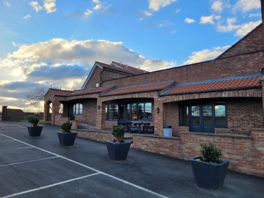 um edifício de tijolos com vasos de plantas num parque de estacionamento em The White Horse Lodge Hotel em Thirsk