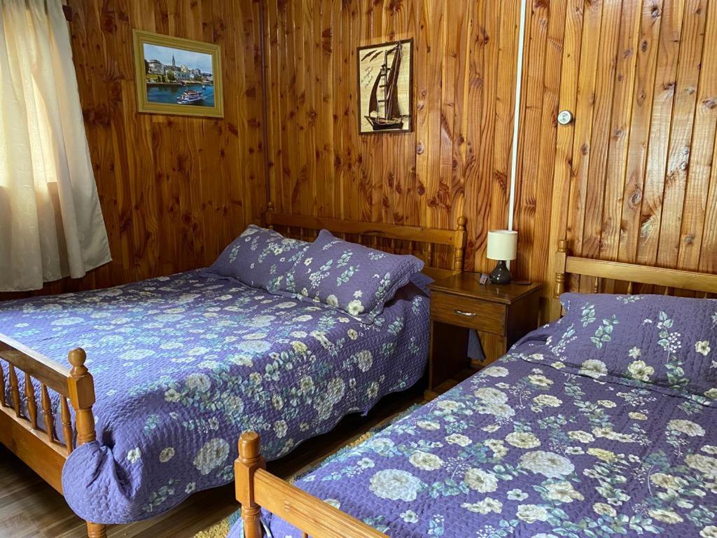 1 dormitorio con 2 camas en una habitación de madera en La posada del turista, en llifen