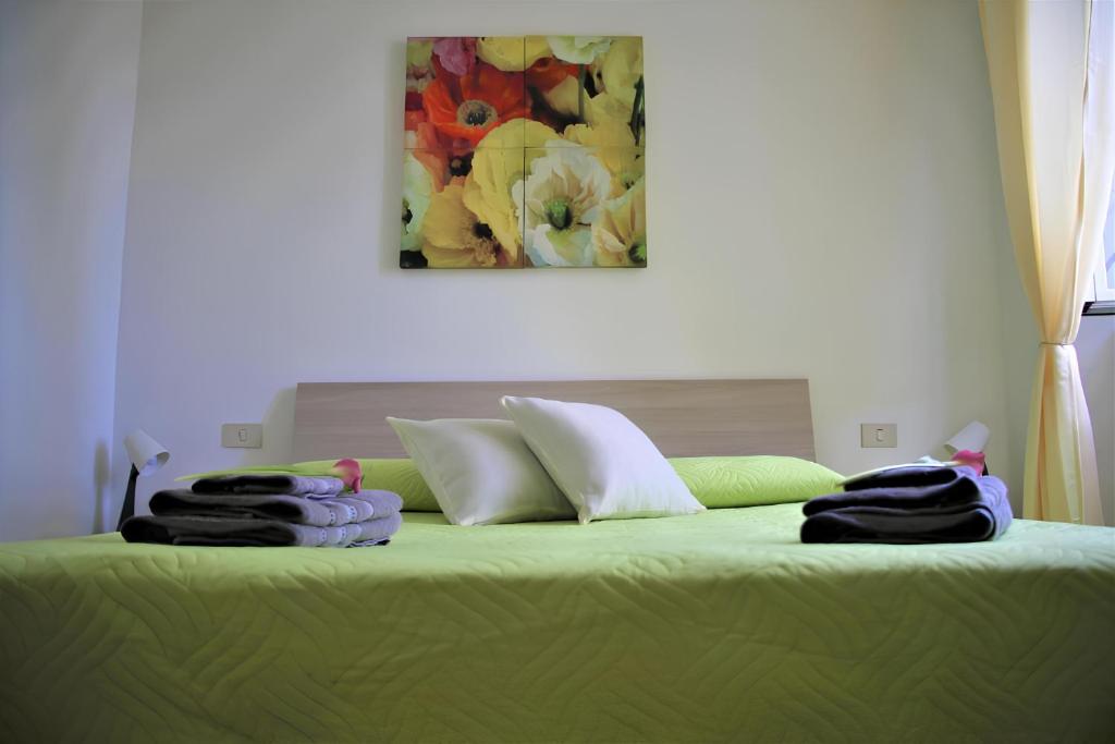 Una cama con sábanas verdes y toallas. en Home & Breakfast La Madonnina 013136-CNI-00001, en Lurago D'Erba 