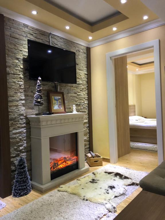 een woonkamer met een open haard en een tv erboven bij Apartment Elvir in Kopaonik
