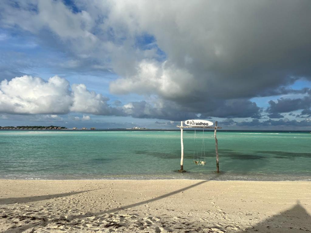 a sign on a beach in the water at Konut by Thakuru in Guraidhoo