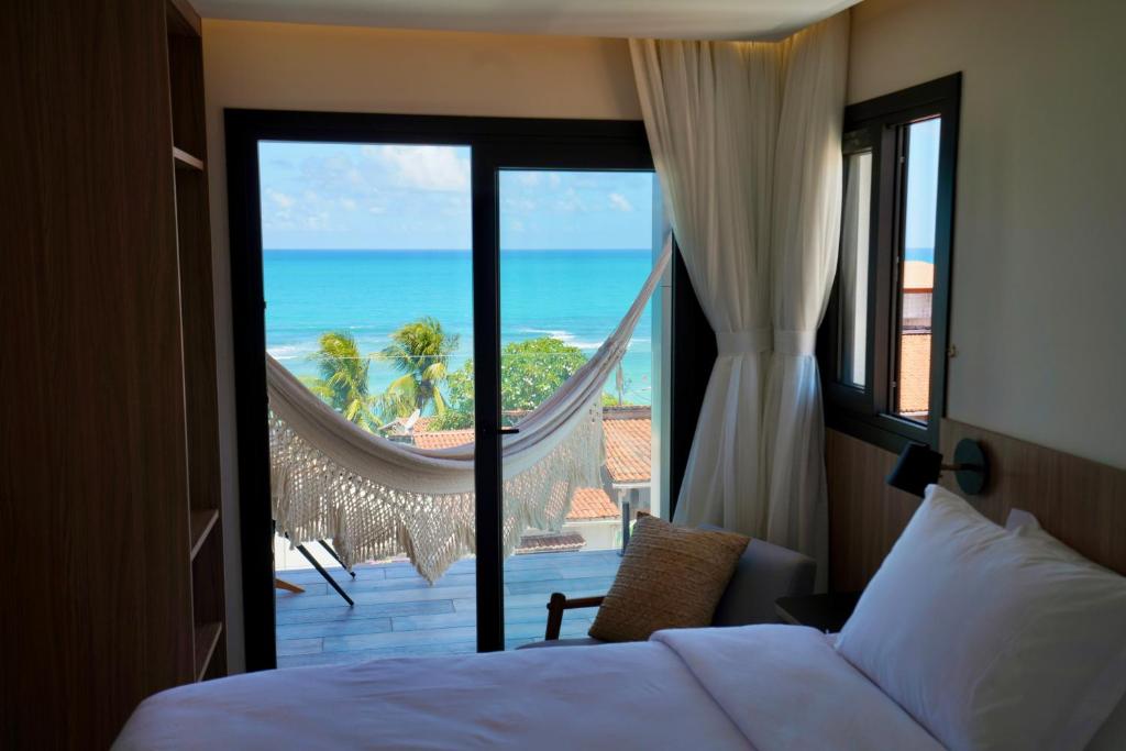 a bedroom with a bed and a view of the ocean at PIPA INN Pousada in Pipa