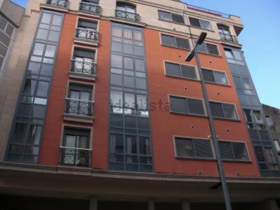 ein hohes orangefarbenes Gebäude mit Fenstern und einer Stange in der Unterkunft Tu dulce hogar, apartamento completo,céntrico con wifi y parking gratuito in Vigo
