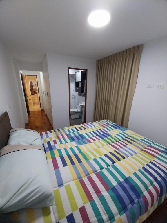ein Schlafzimmer mit einem großen Bett mit einer bunten Decke in der Unterkunft Edificio parque residencial in Lima