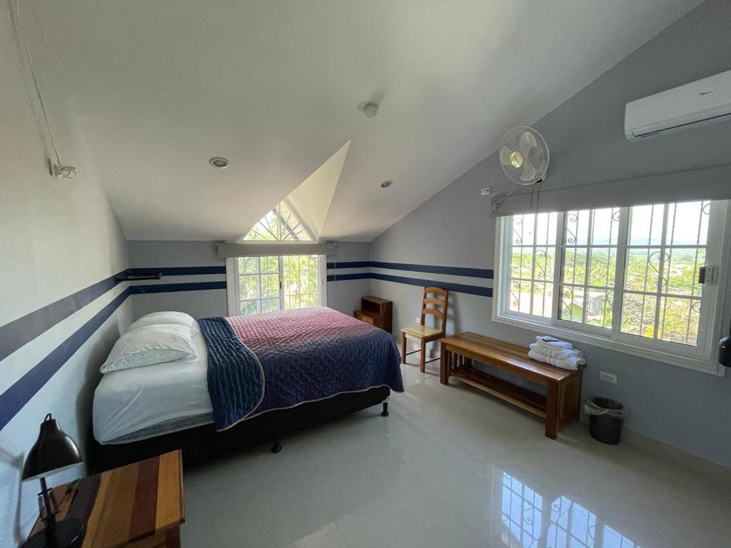 um quarto com uma cama, uma secretária e 2 janelas em Marissa Guest House em San Ignacio
