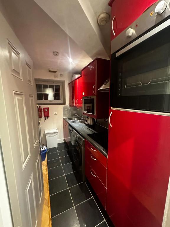 a kitchen with red cabinets and a red microwave at Doric apartment in London