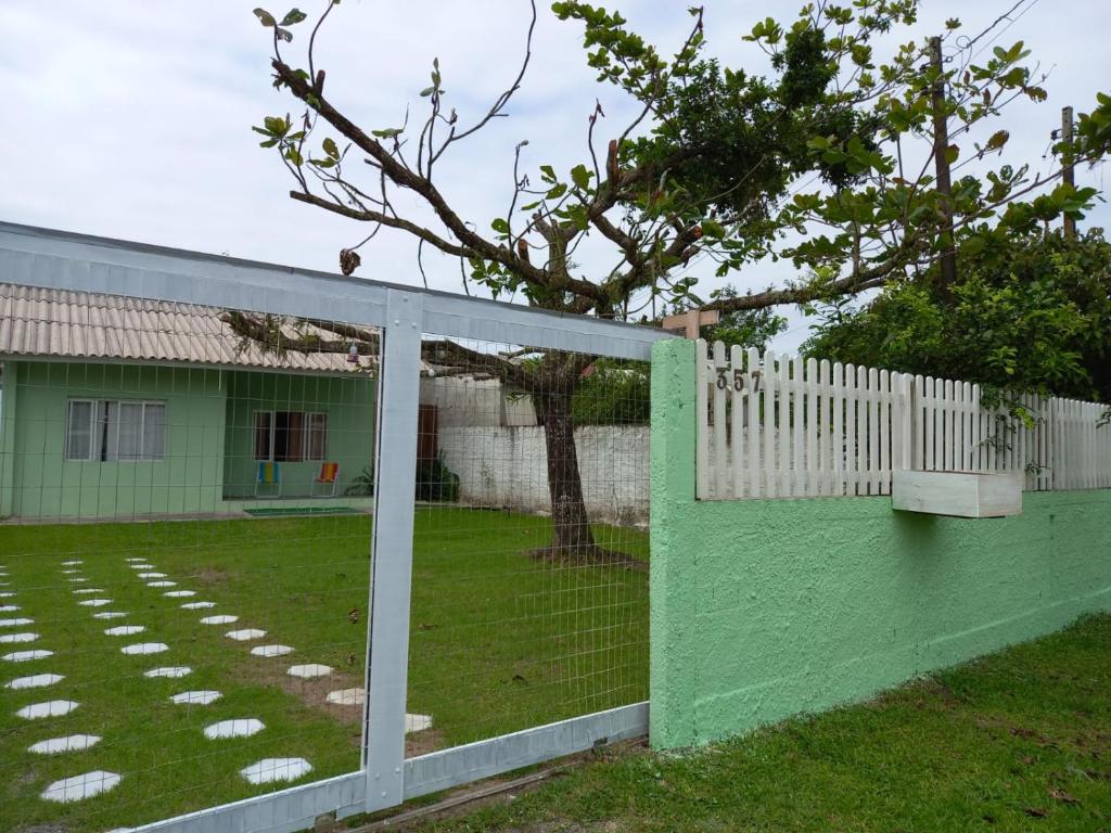 a green fence with a tree in the yard at Casa aconchego com piscina in Guaratuba