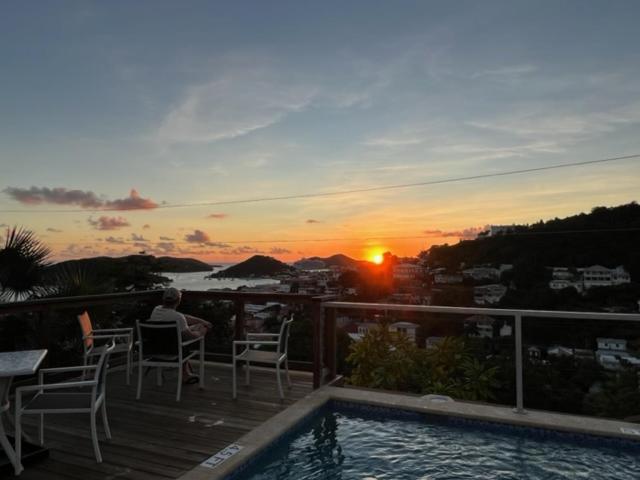 een man die op een dek zit te kijken naar de zonsondergang bij The Green Iguana Hotel in Charlotte Amalie