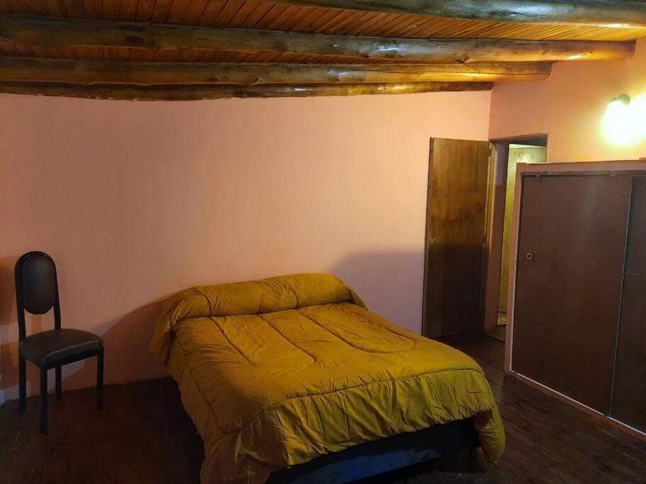 a bedroom with a bed and a chair in it at Hermosa Cabaña Duplex Malargüe. in Malargüe