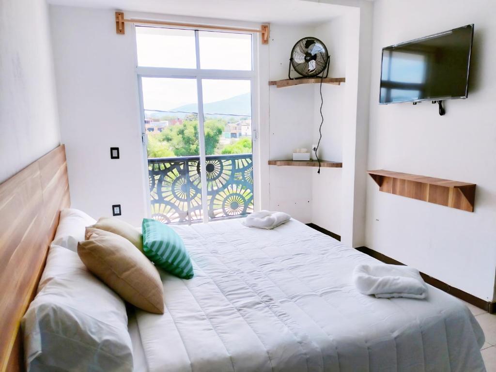 Schlafzimmer mit einem großen Bett und einem Fenster in der Unterkunft Aqua Suites in Oaxaca de Juárez