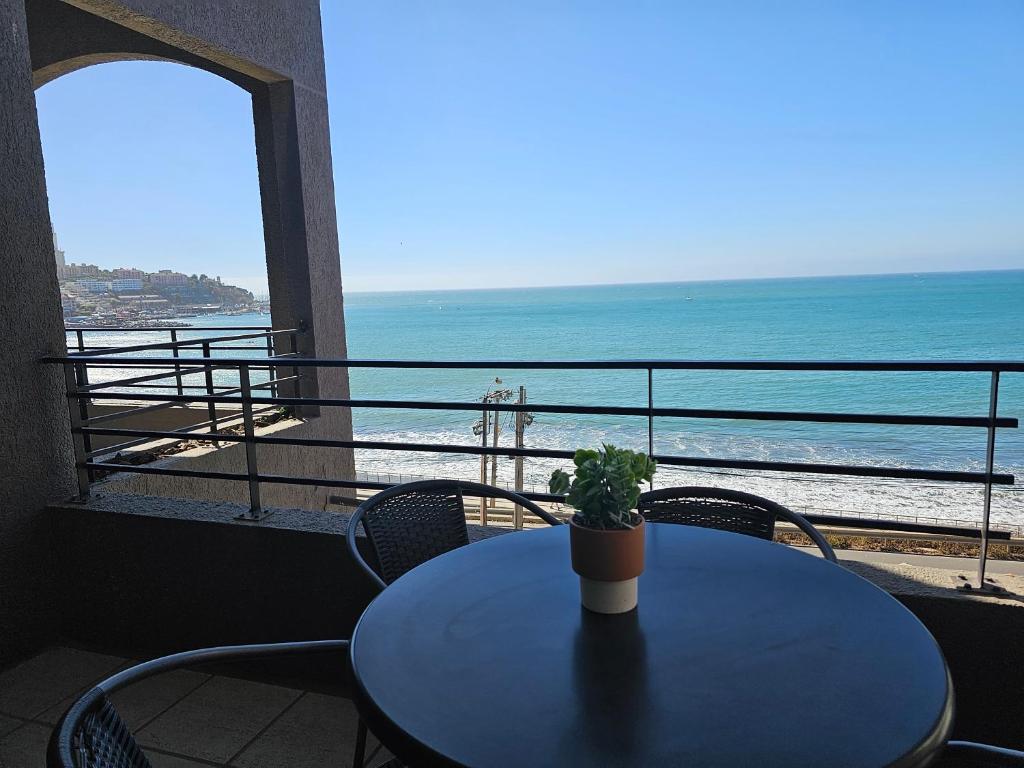 a table with a potted plant on top of a balcony with the ocean at Espectacular Bahía Bonita depto 43 in Concón