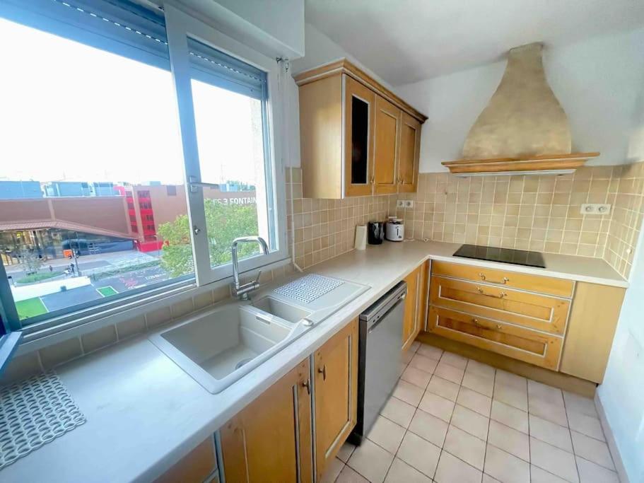 eine kleine Küche mit einem Waschbecken und einem Fenster in der Unterkunft Appartement centre ville tout confort et spacieux in Cergy