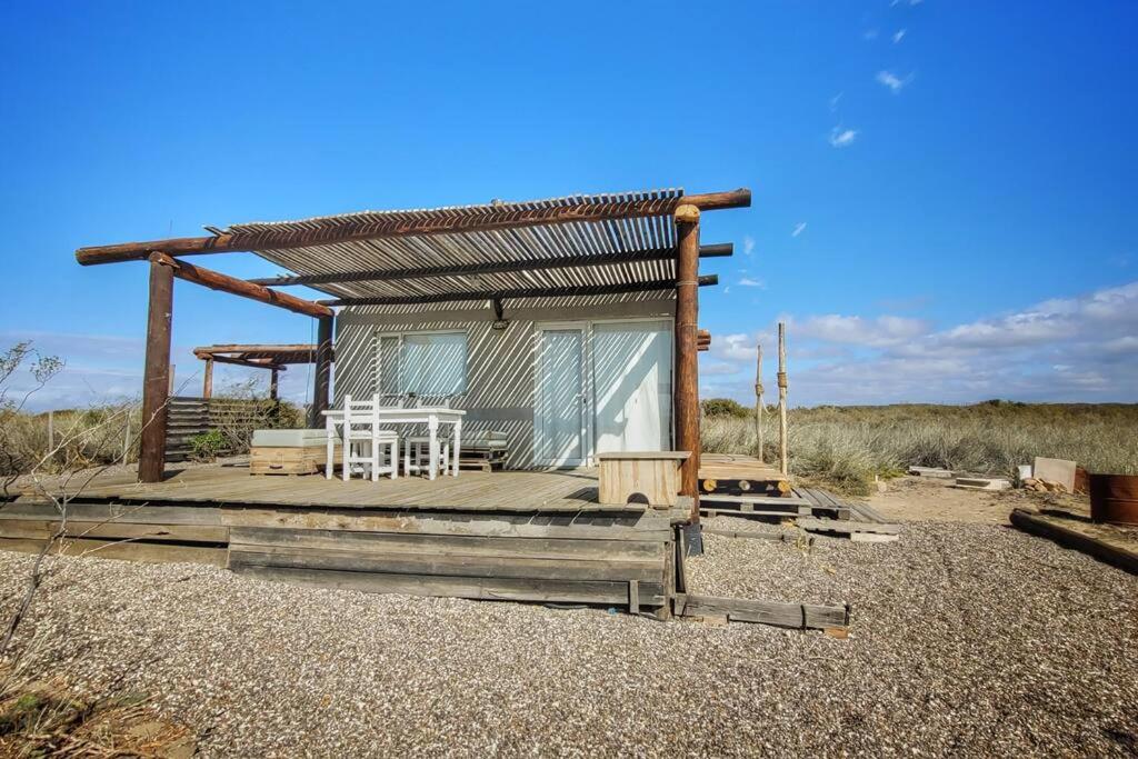 a small house with a roof on a wooden deck at Mandalei, Refugio De Mar in Las Grutas