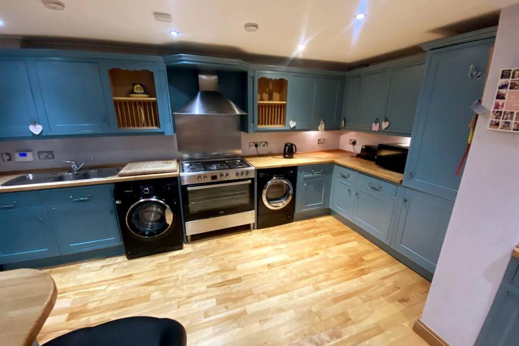 een keuken met blauwe kasten en een wasmachine en droger bij Boss Breaks-Luton in Luton