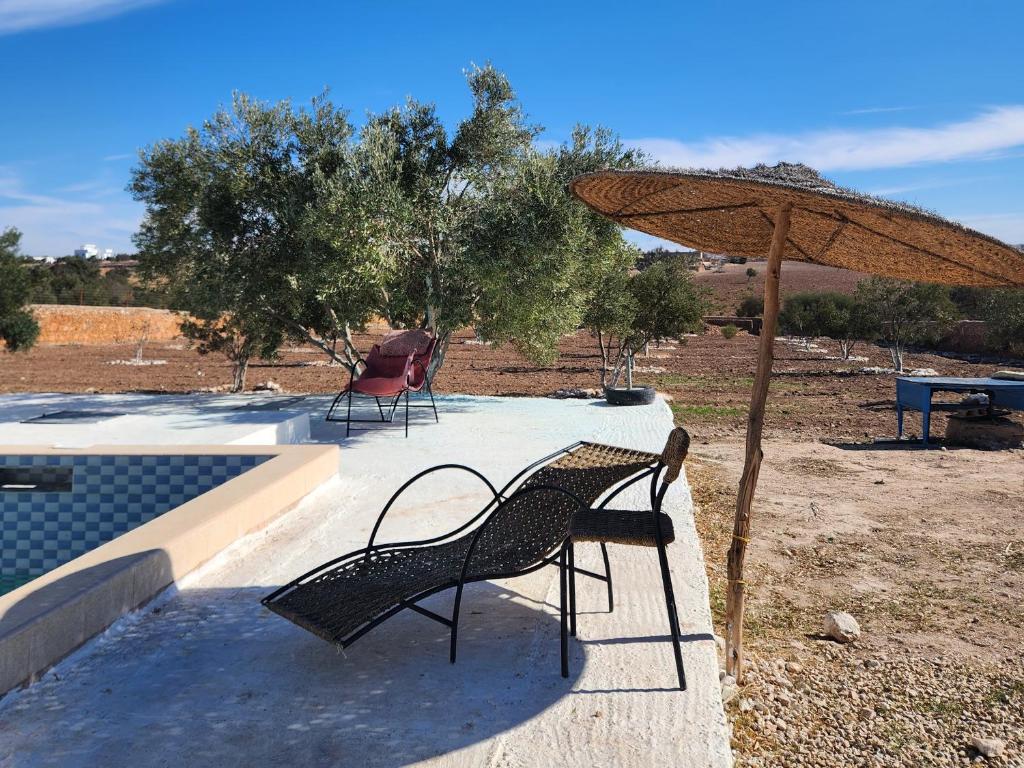 dos sillas y una sombrilla junto a una piscina en Villa mgm, en Bou Mkila