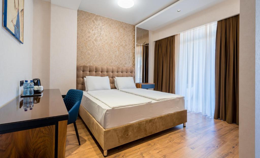 una camera d'albergo con letto e scrivania di Olympus Hotel By Umbrella a Tbilisi City