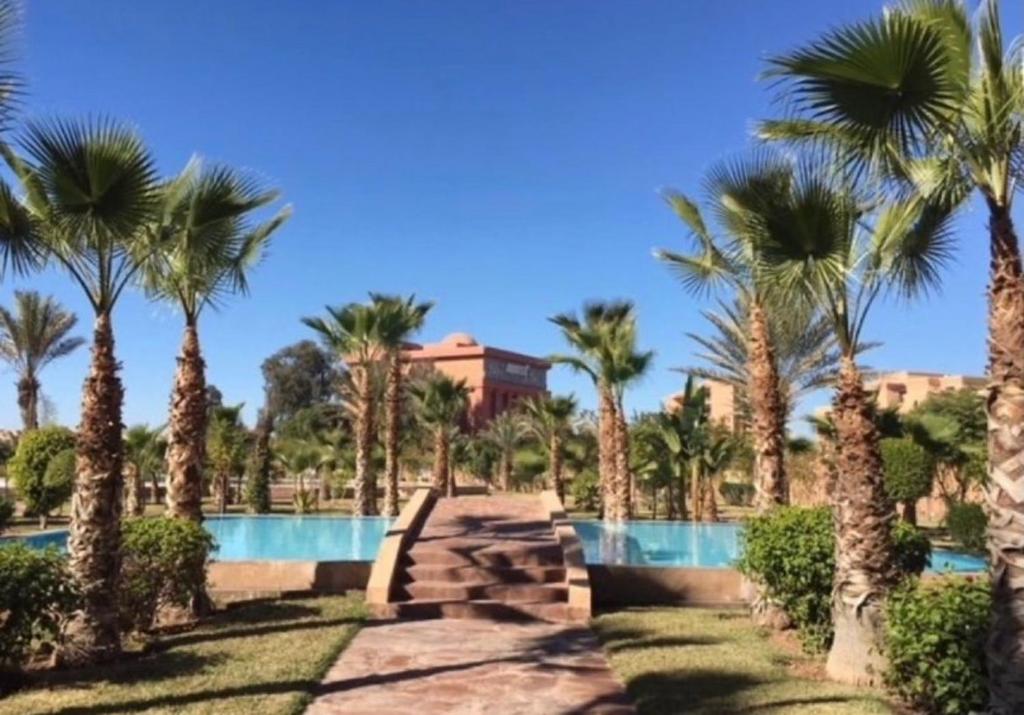een resort met palmbomen en een zwembad bij Appartement Hivernage M Avenue in Marrakesh