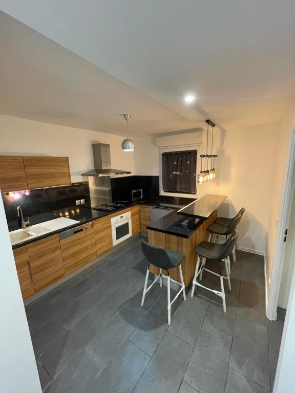 a kitchen with a counter and some chairs in it at Superbe logement Paris Stade de France in La Courneuve