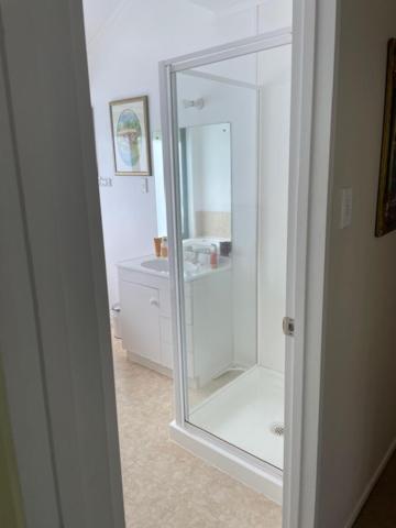 a bathroom with a glass shower stall and a mirror at Annabells B&B in Whitianga