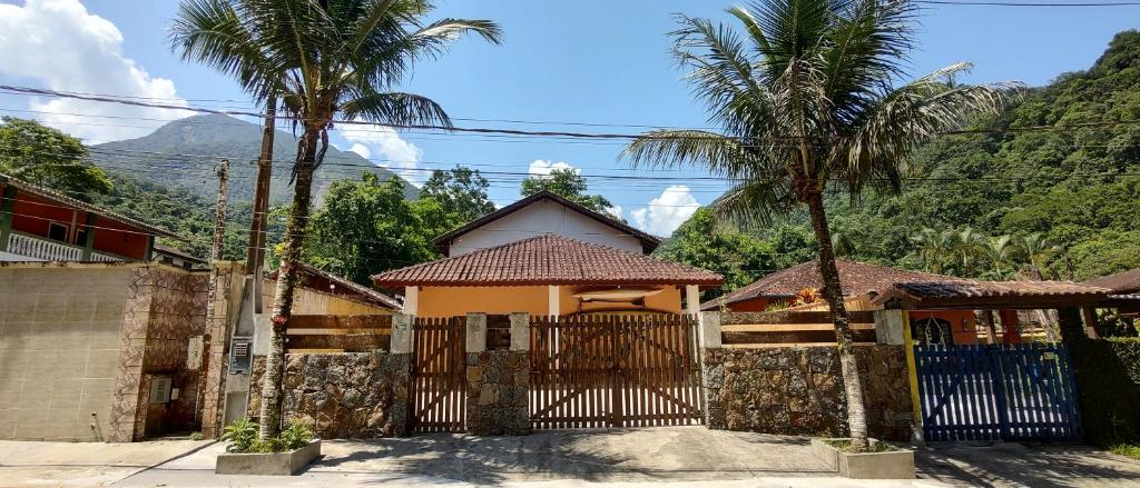 a house with a gate and a palm tree at Morada Cristal in Caraguatatuba