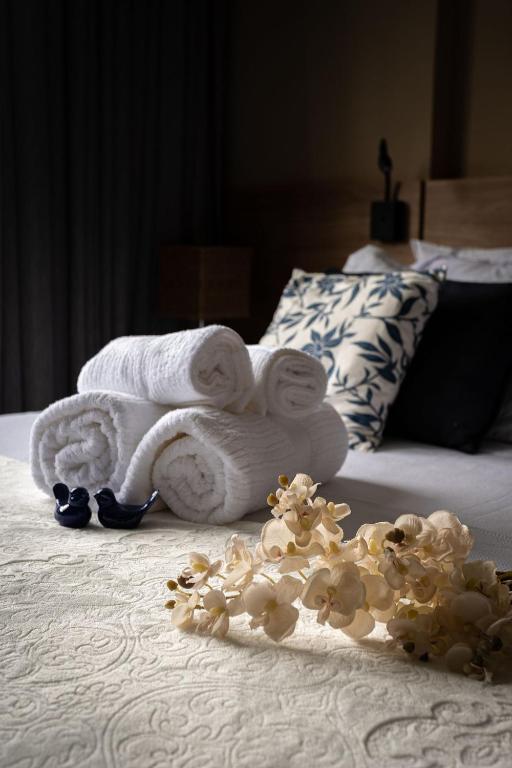 a pile of towels and flowers on a bed at Studios de Luxo Granja Brasil Itaipava in Itaipava