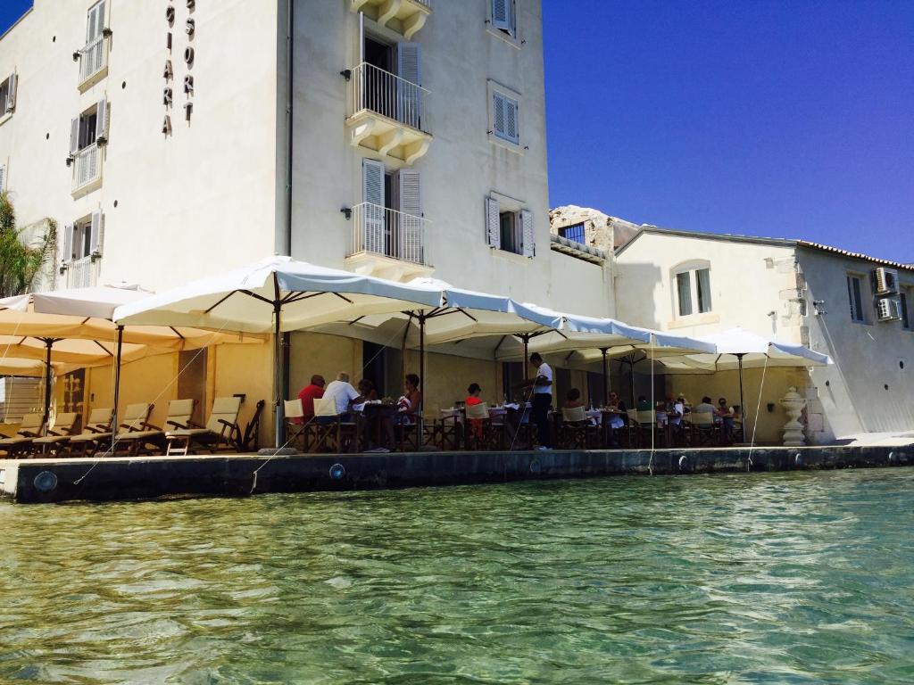 um restaurante com mesas e guarda-sóis ao lado de um edifício em Musciara Siracusa Resort em Siracusa