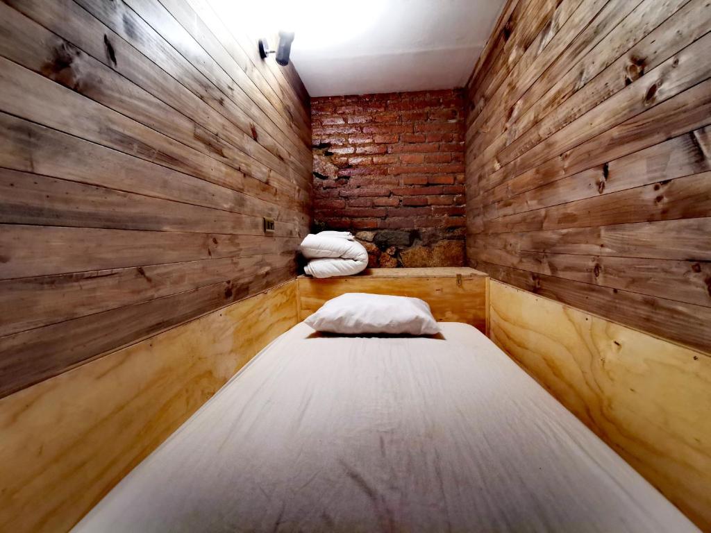 Habitación pequeña con cama y pared de ladrillo en Hostal Licanantay, en Valparaíso
