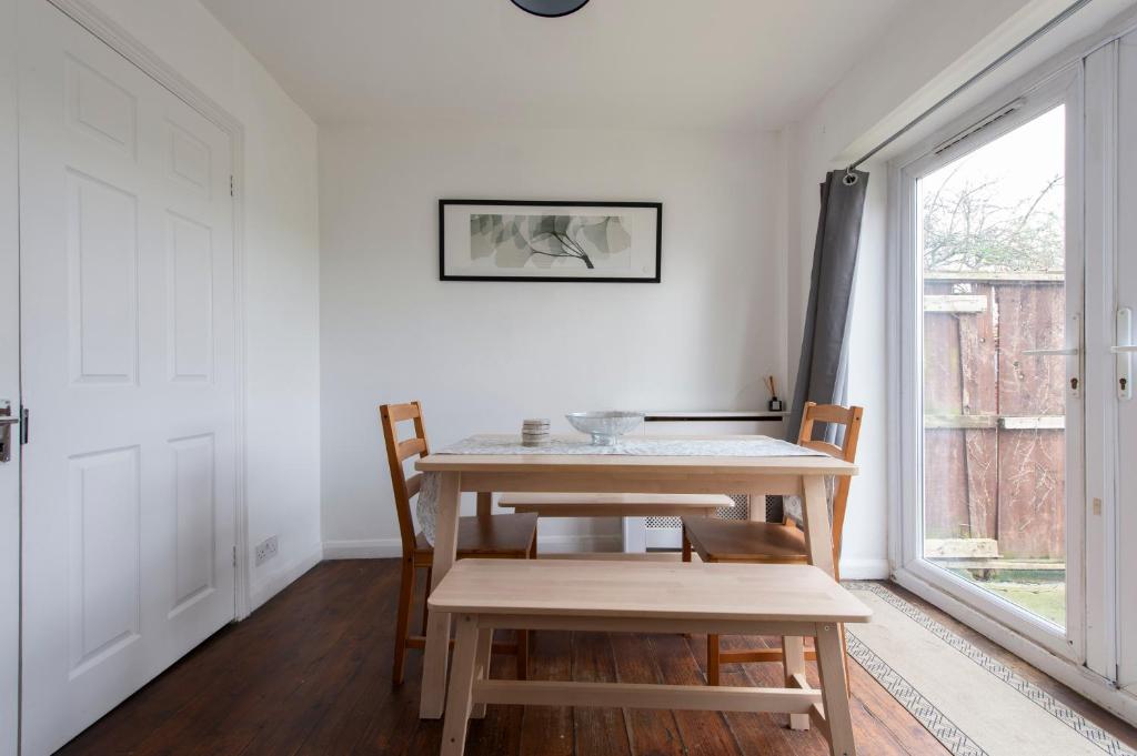 uma mesa e cadeiras num quarto com uma janela em Chingford charm great for families and contractors em Ponders End