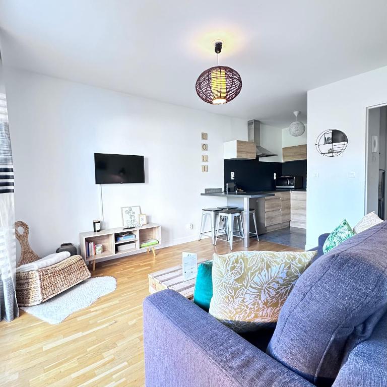 a living room with a blue couch and a kitchen at Beautiful apartment * parking* Disneyland 10 min in Montévrain