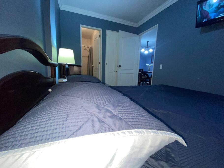 een slaapkamer met een groot bed en een tv aan de muur bij Tu hogar en la mitad del mundo. in Quito