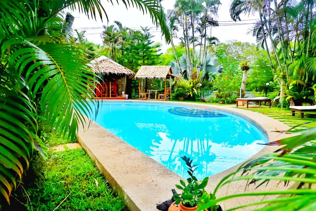a swimming pool in a garden with a house at Kingsacre in Nai Yang Beach