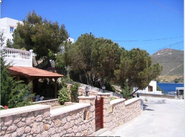 a stone wall next to a building with trees at Studios Irene in Skala