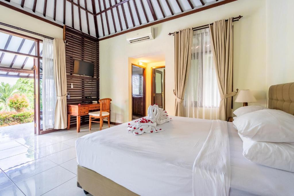1 dormitorio con 1 cama blanca grande y escritorio en Taman Surgawi Resort & Spa, en Jasri