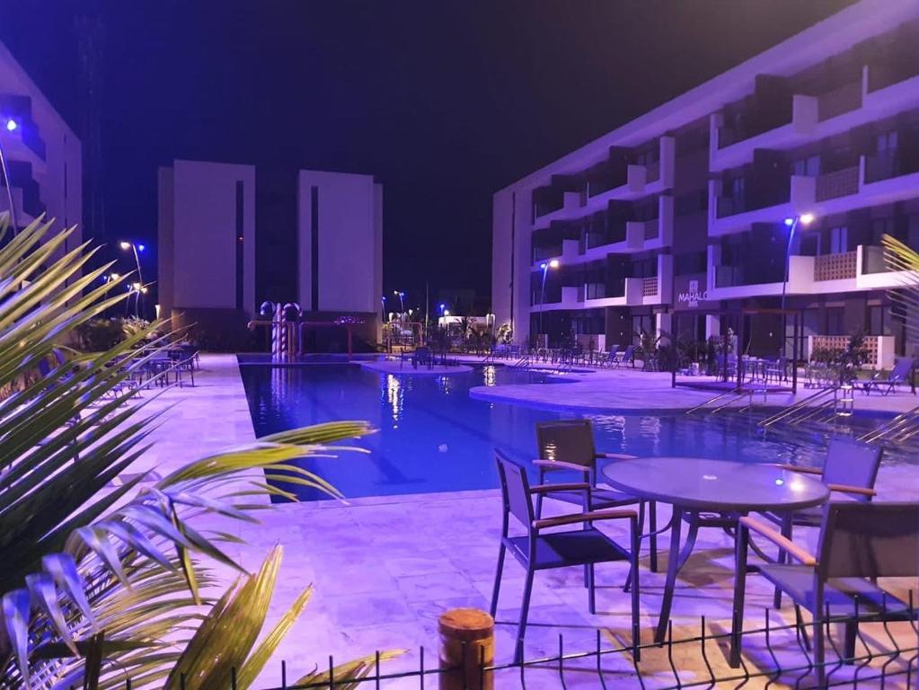 - une piscine avec une table et des chaises la nuit dans l'établissement Mana Beach Pono by Flats Prime, à Porto de Galinhas