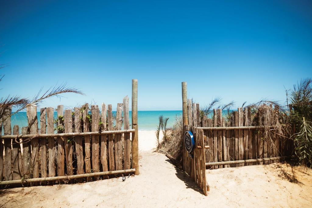 una valla de madera en la playa con el océano en el fondo en Casa Mar Pé na Areia, en Caraíva