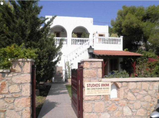 a white house with a stone fence and a sign at Studios Irene in Skala