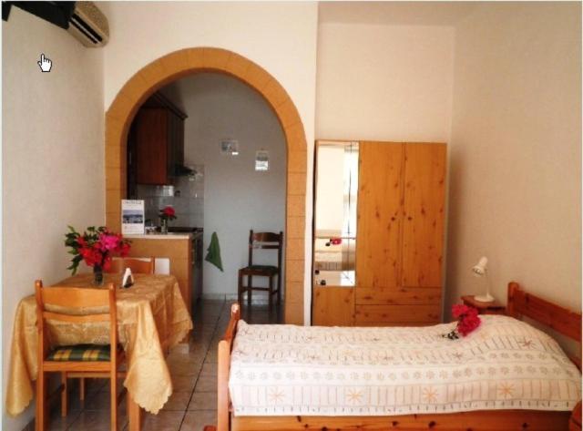 a bedroom with a bed and a table and a kitchen at Studios Irene in Skala