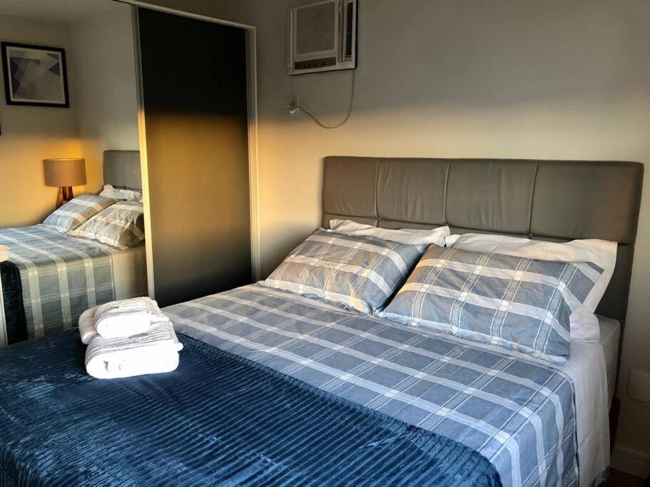 um quarto com 2 camas com um cobertor azul e branco em Apartamento Central Park Oktoberfest em Blumenau