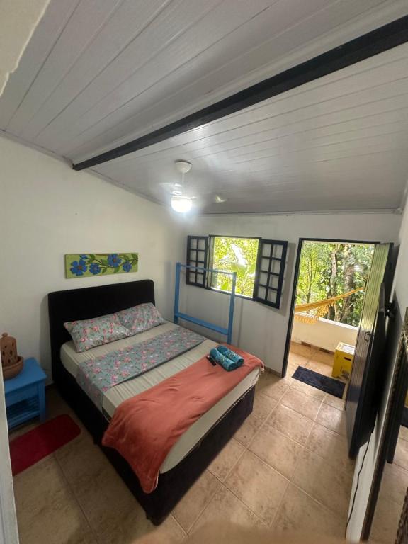 1 dormitorio con 1 cama en una habitación con ventanas en ÓTIMA NOTA - CASA DO RIO DE PEDRAS Próximo Praias , Ilhas ,Cachoeiras e Centro Histórico, en Paraty