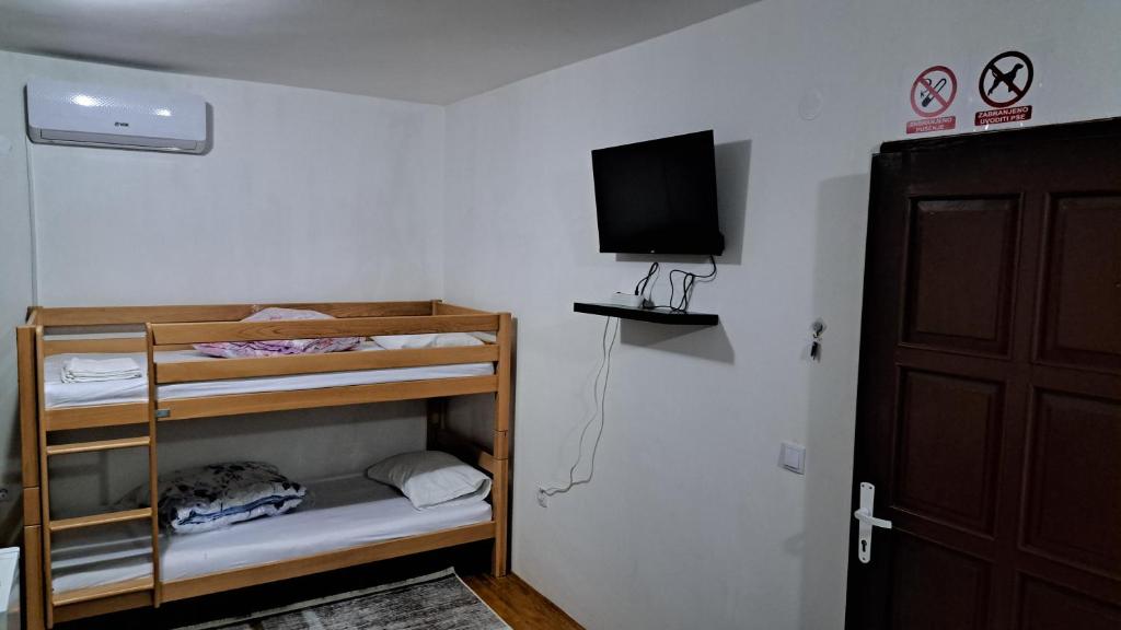 a room with bunk beds with a television and a door at Apartmani Saraj in Sarajevo